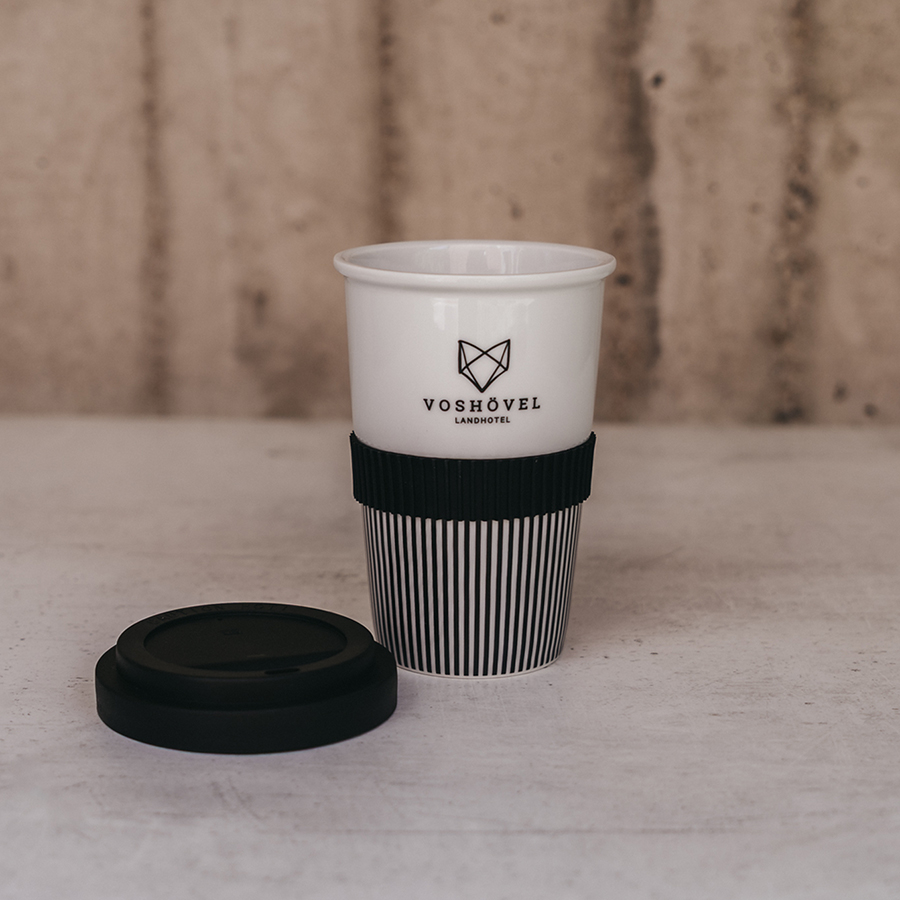 Schwarz-weißer Kaffe-to-go Becher mit dem Voshövel Logo und geöffnetem Deckel